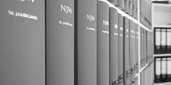 Mehrere Reihen schwarzer Bücher mit NJW-Schriftzug stehen auf einem Regal.